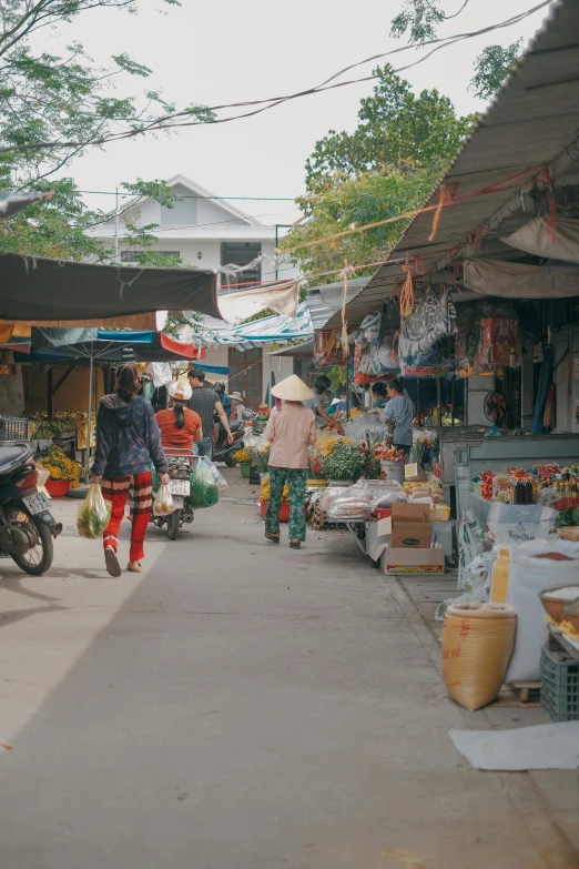 a market with people shopping and standing on a sidewalk