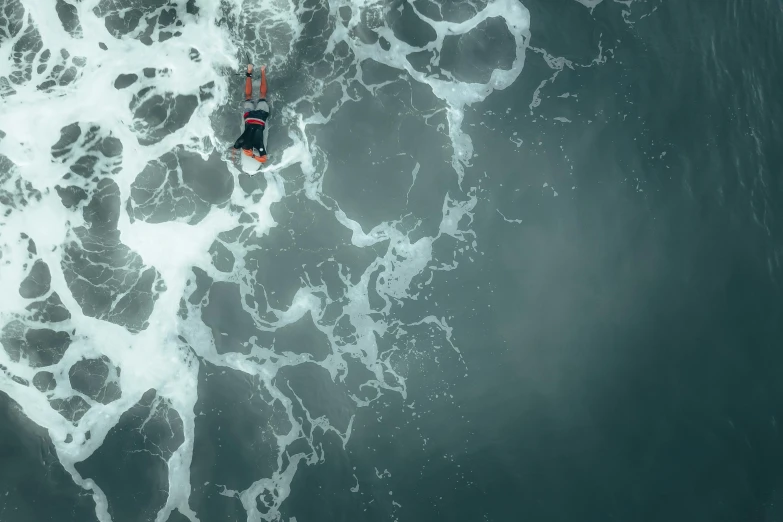 an aerial view of an ocean with a person riding a surfboard