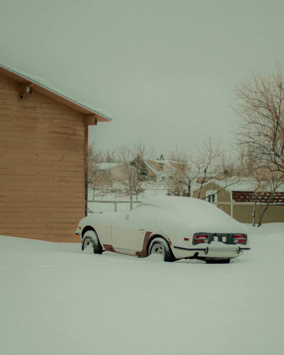 a snow covered car sits in a driveway