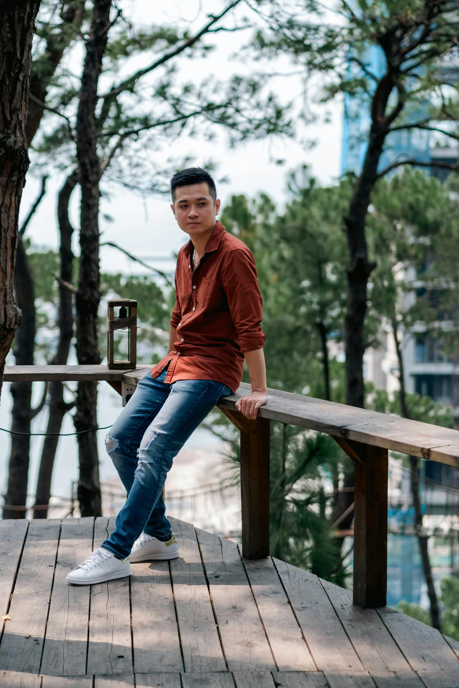 a man leaning against a tree sits on a rail