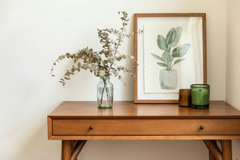 the small mirror is next to a table with a vase of flowers