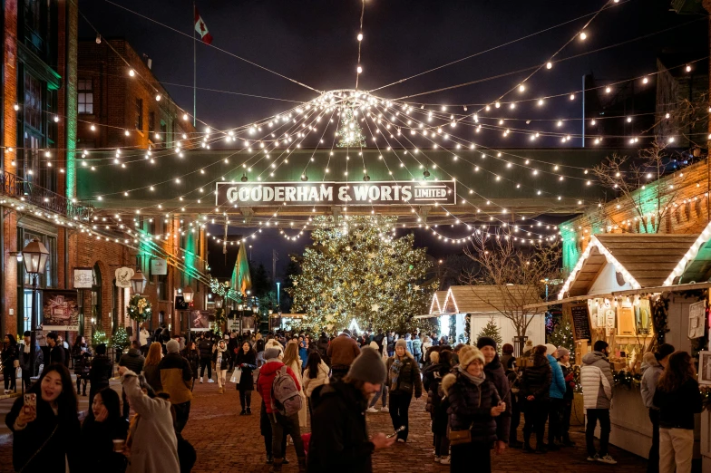 there are many people walking underneath a decorated christmas tree