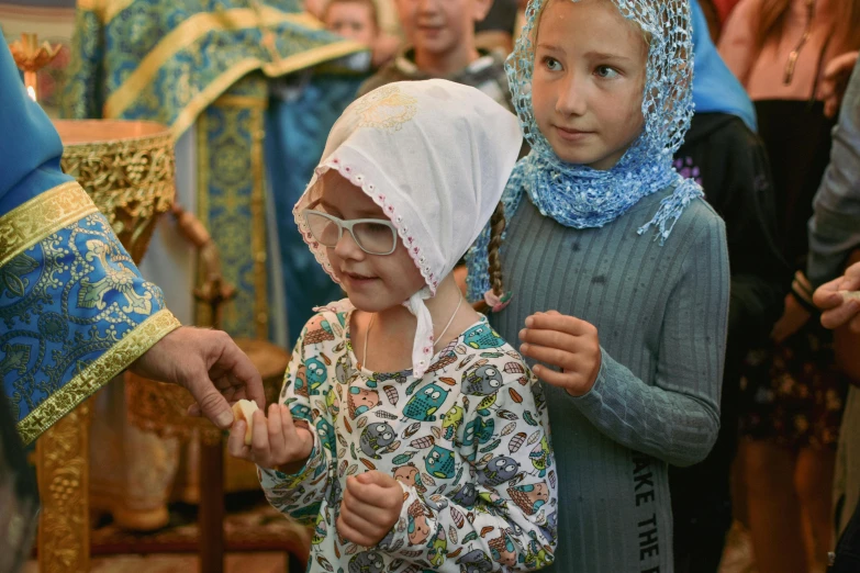 two young children standing in front of the priest