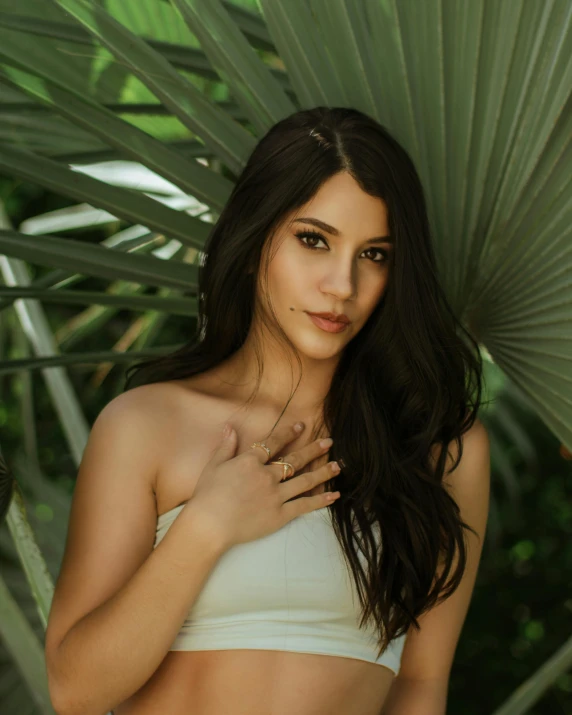 a woman posing in front of plants and a leafy green background