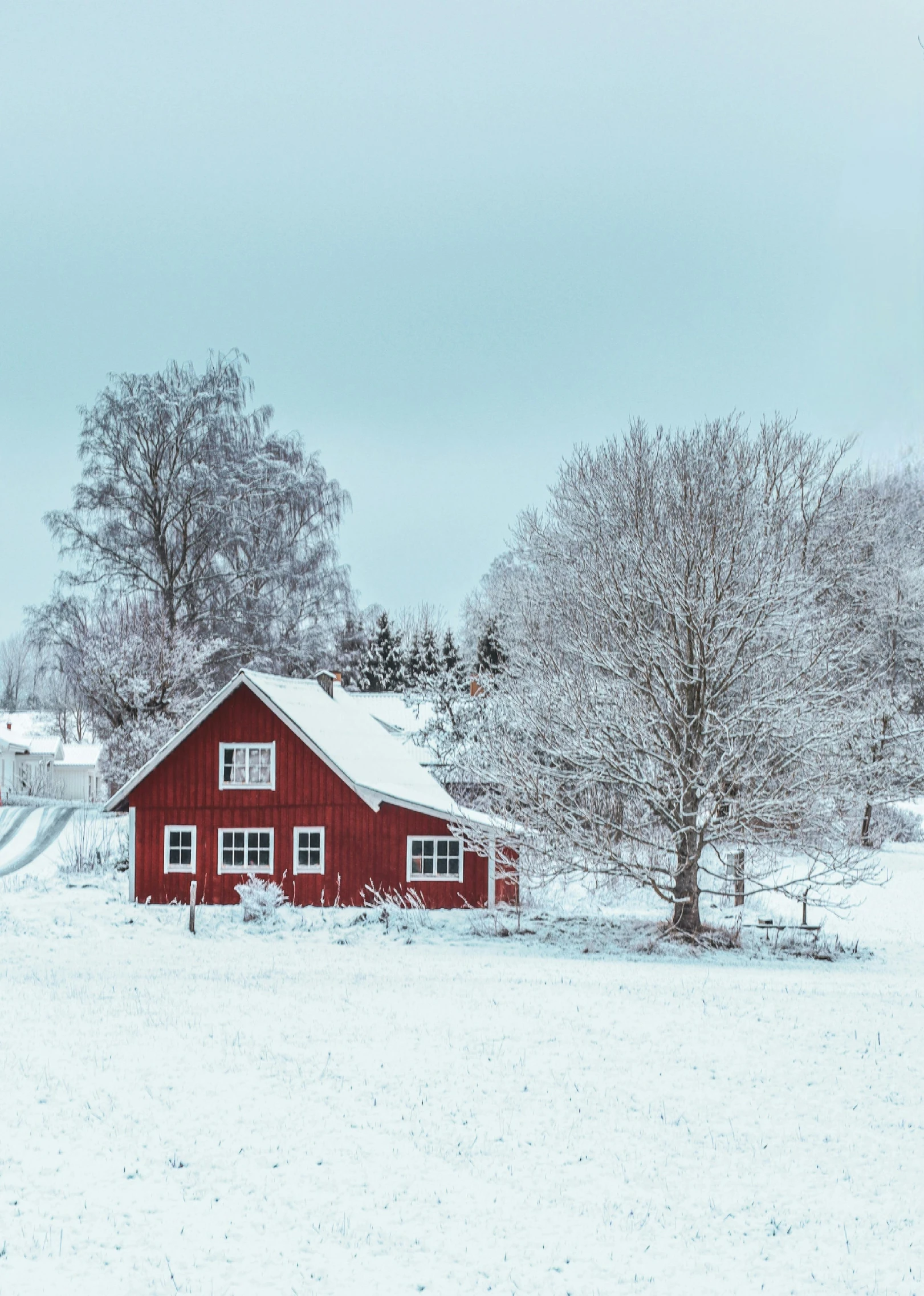 a red house sits on a snowy, clear day