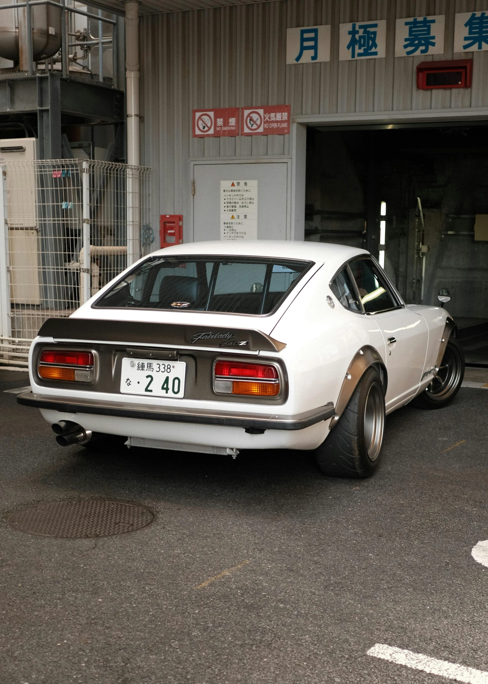 white, muscle car parked in a garage with large doors