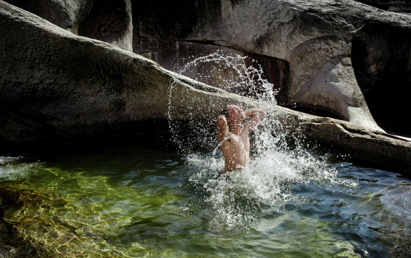 a man playing in the water near some large rocks