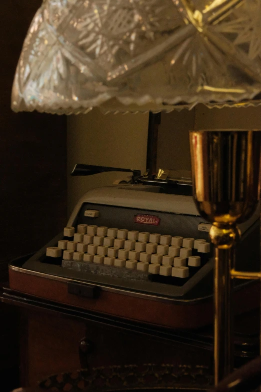 an old fashioned typewriter on a table next to a lamp