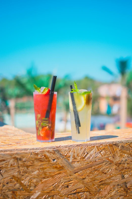 two colorful drinks sitting on a wooden ledge