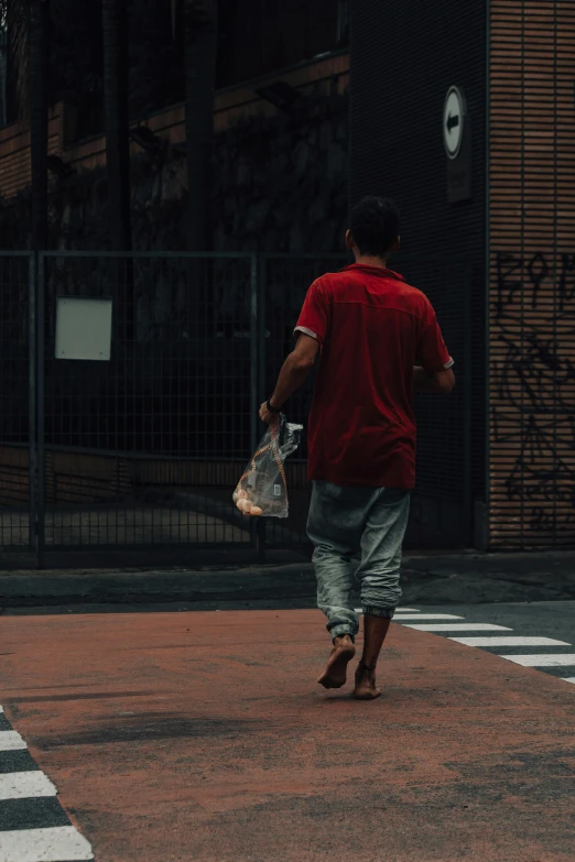 man walking on street carrying a bag and wearing slippers