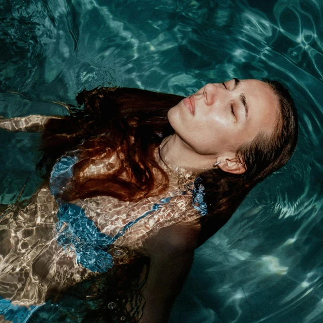 woman in blue dress floating in water near shore