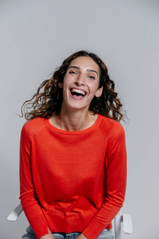 a woman sitting on top of a chair and laughing