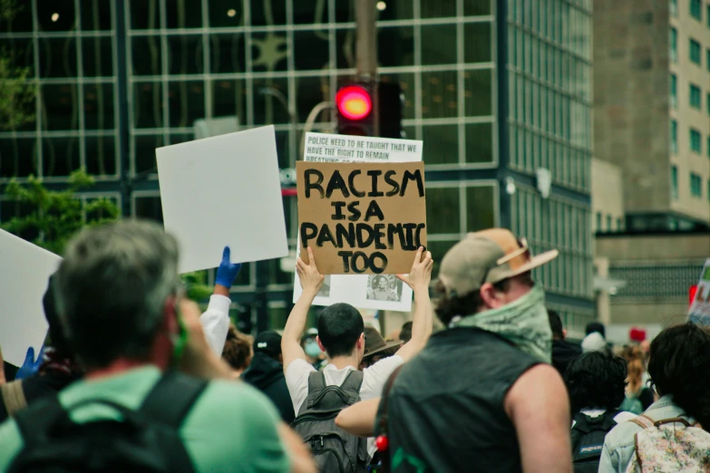 a man holding up a sign in the middle of a crowded street