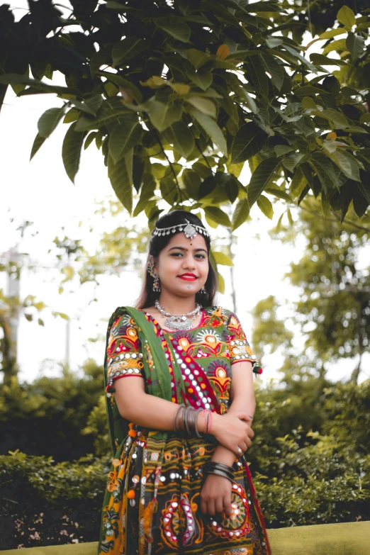 a woman in brightly colored clothing standing next to a tree