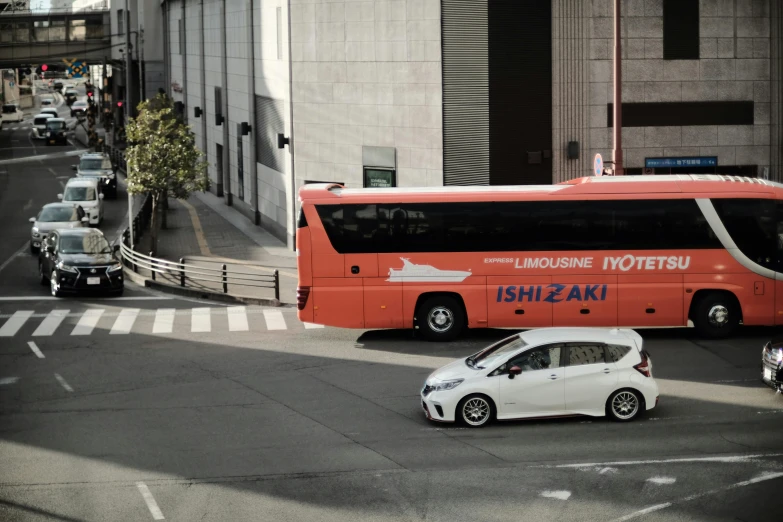 a red bus on the side of a road with a small white car parked next to it