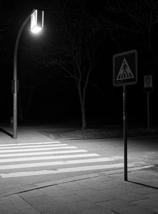 a cross walk and street sign on a dark road at night