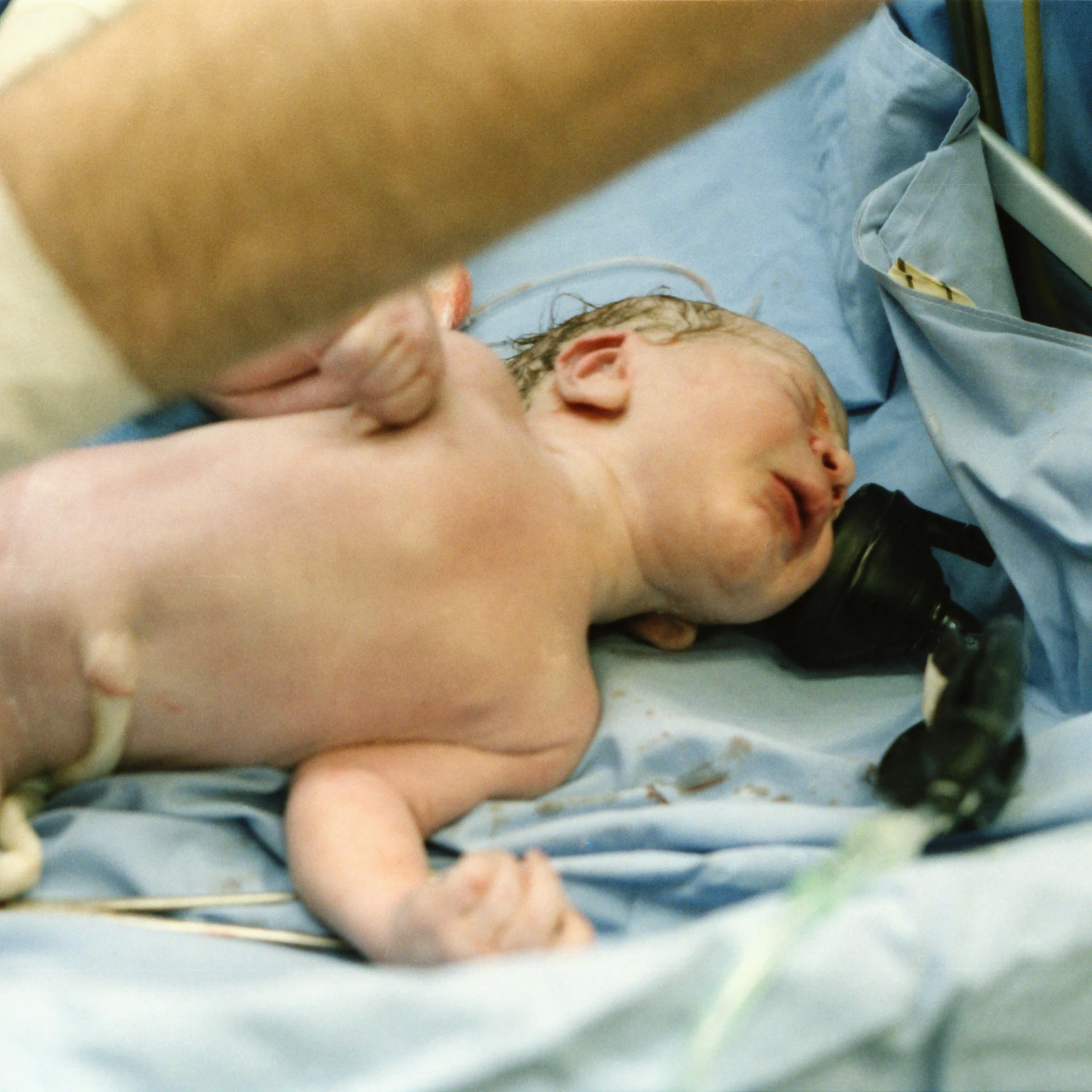 a baby laying in a bed while being fed by a nurse