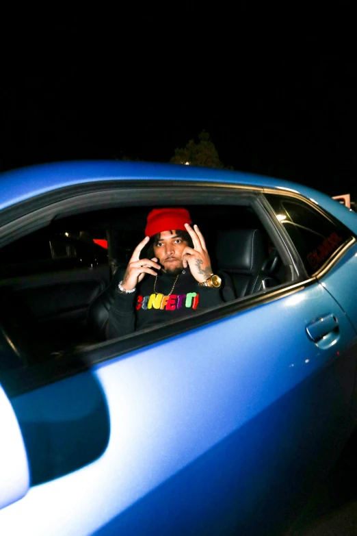 a young man sitting in the drivers seat of a blue car