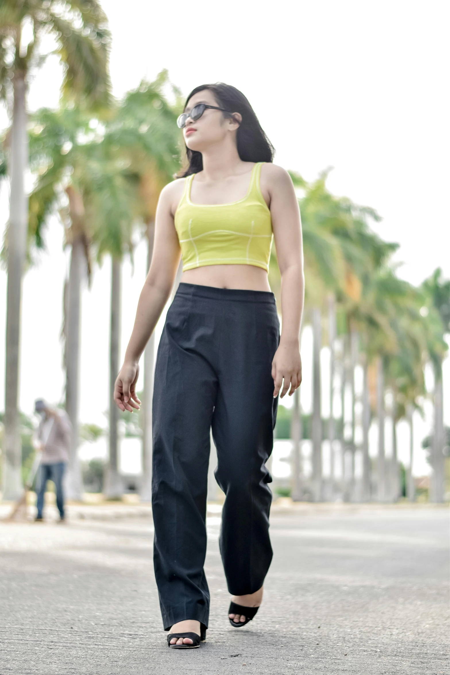 a young woman in tight pants and crop top is looking away