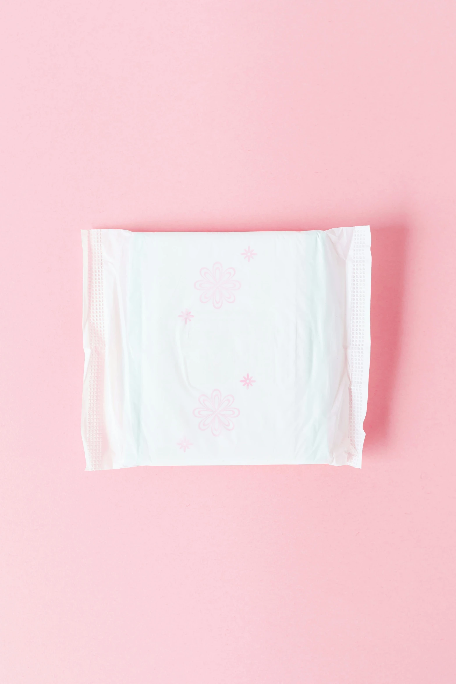 an unisex baby handkerchief sitting on a pink surface