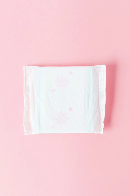 an unisex baby handkerchief sitting on a pink surface