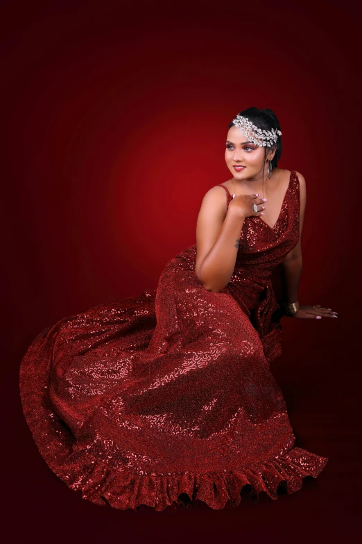 a woman wearing a dress sitting against a red wall