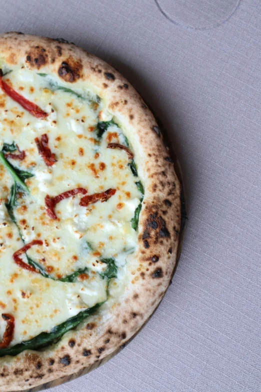 small, crusty pizza sits on top of a table