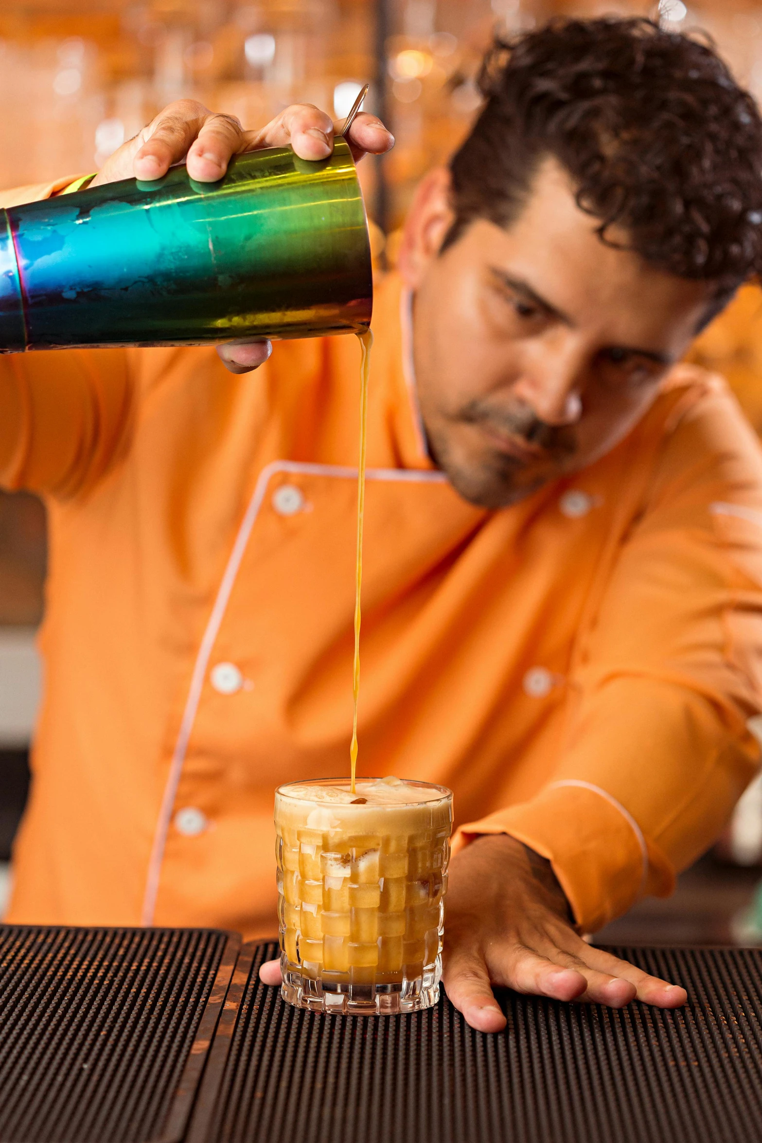 a man pouring soing into a cocktail in a glass