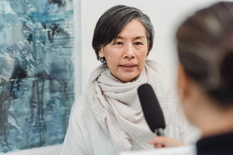 a person sitting in a chair talking to a woman