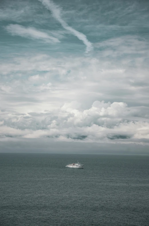 a boat in the middle of an ocean under clouds