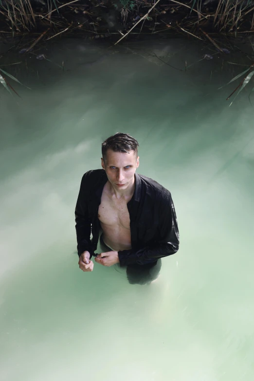 man in water looking up with grass near his back