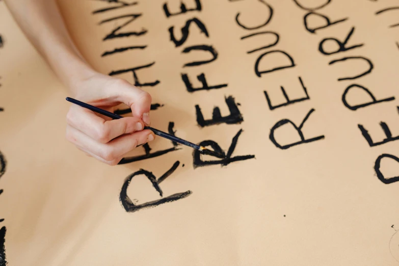 someone using a sharpie to write letters onto paper