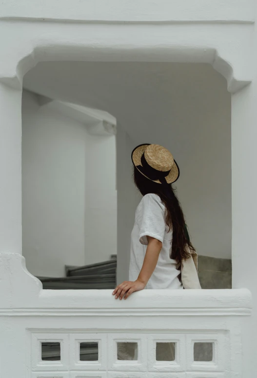 a woman in a straw hat looking over a fence