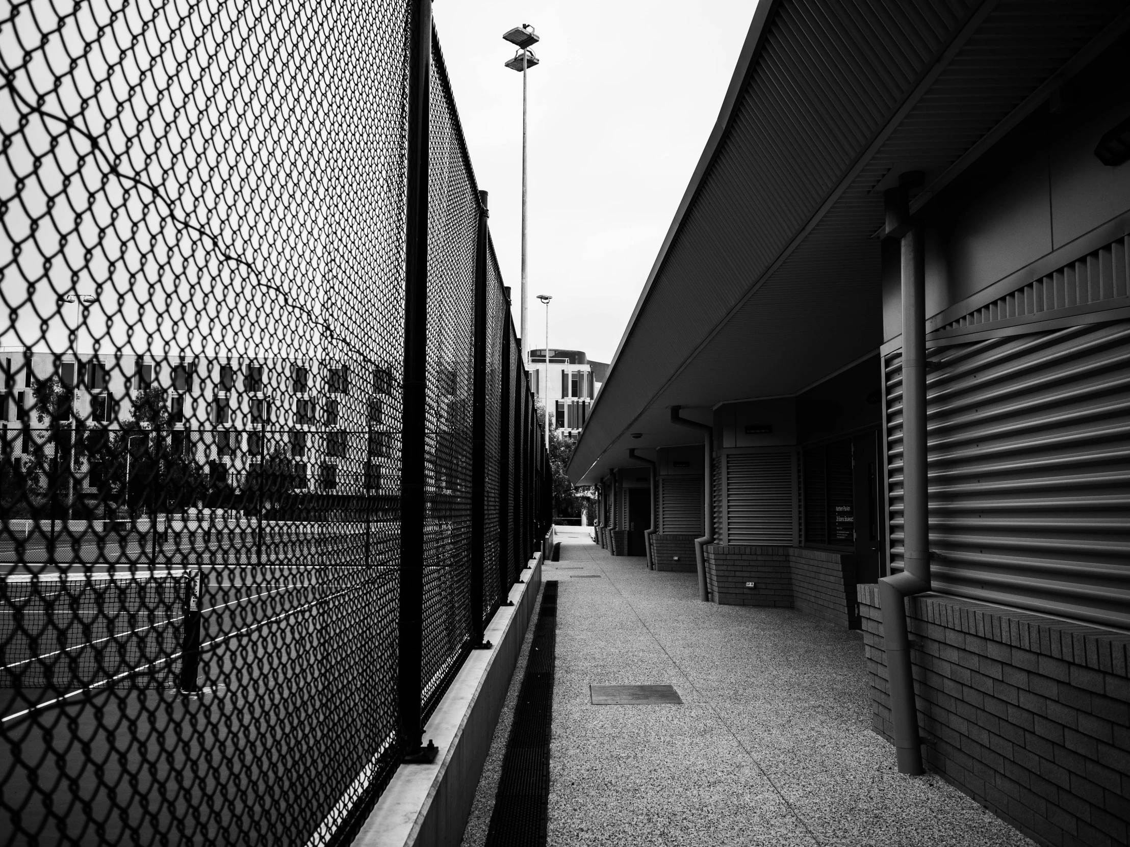 the building is surrounded by a fence that has a long shadow