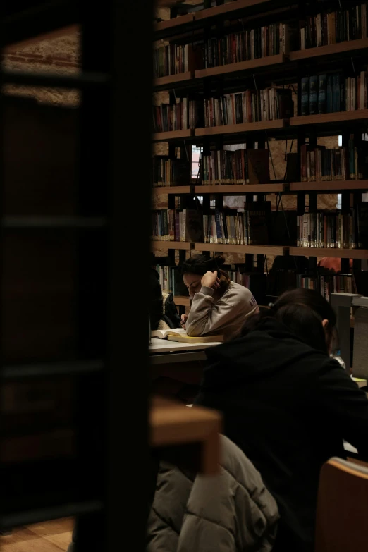 people sit at a table in front of a bookcase