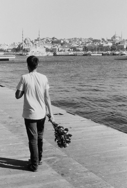 a couple walks along the water holding flowers