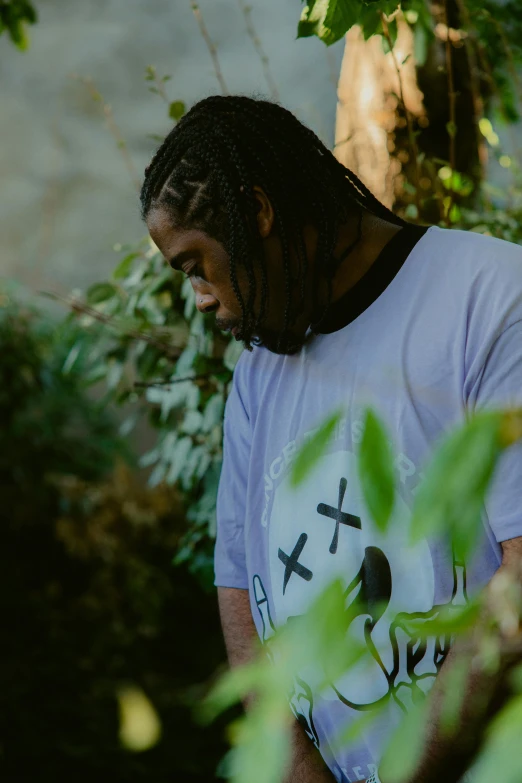 a man with long hair standing in the forest