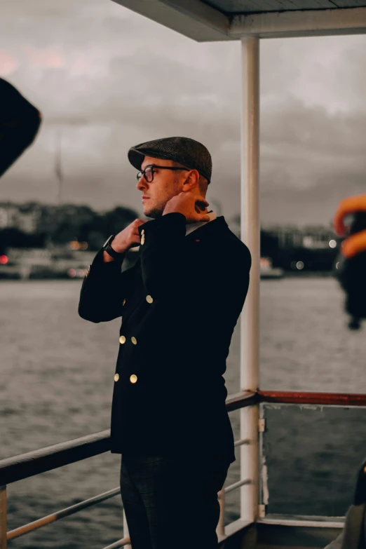 man in naval uniform adjusting his hat near water