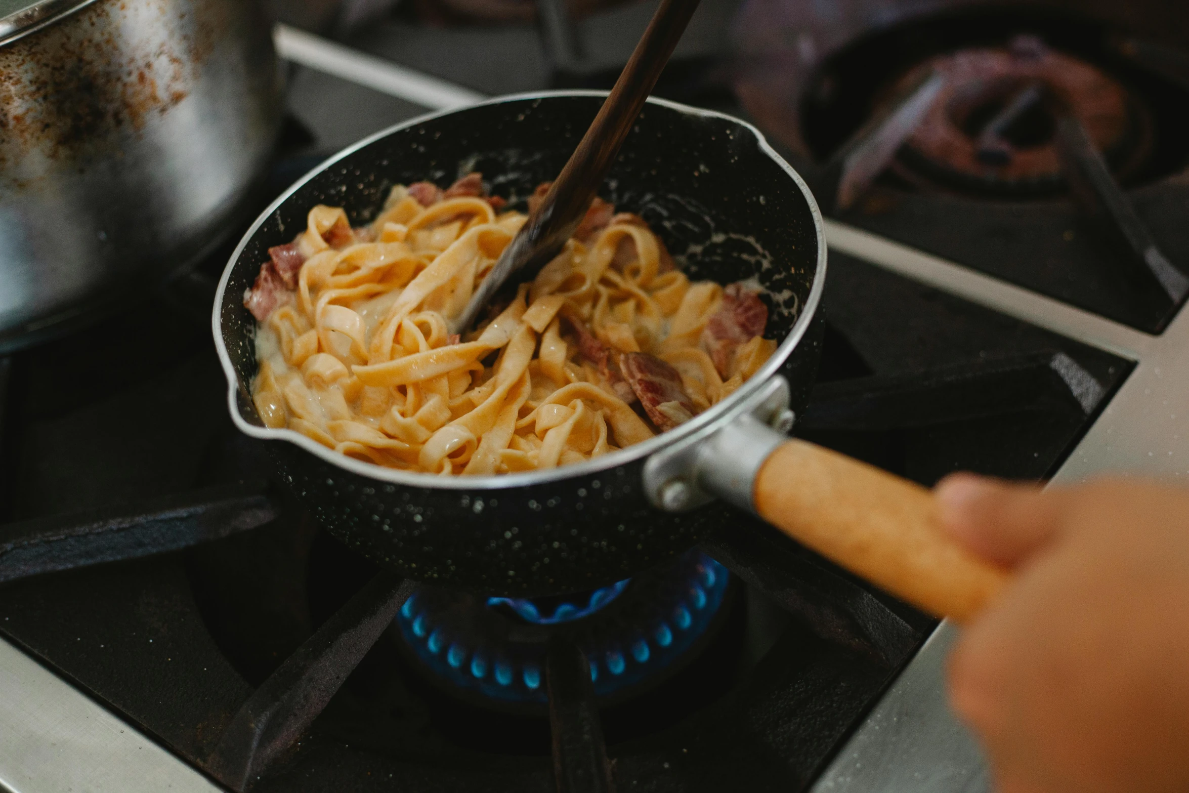 someone is pulling cooked pasta out of a frying pan