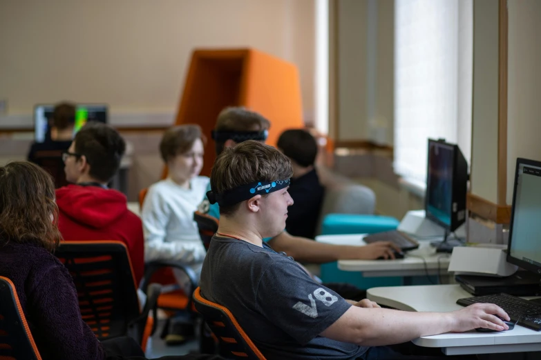 a group of children are in a classroom working on computers