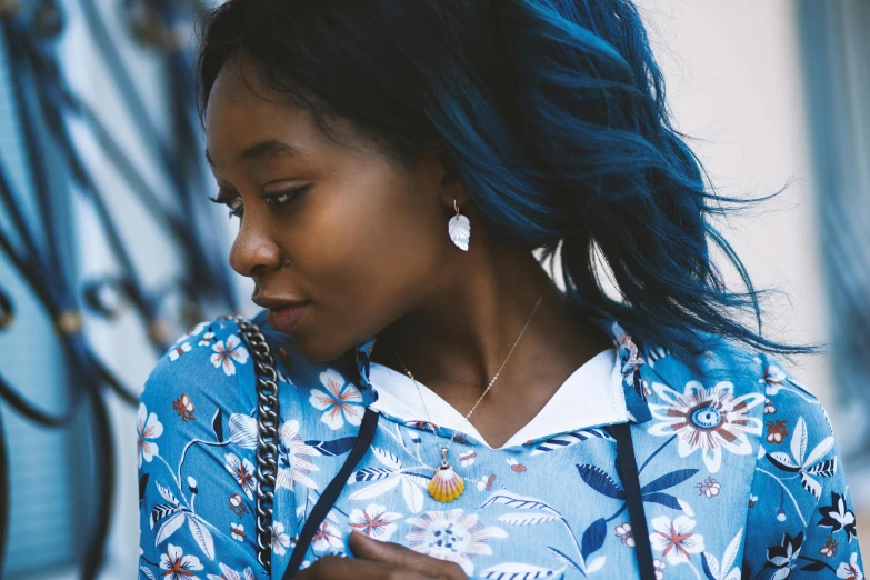 a woman with blue hair and earrings on looking at her phone