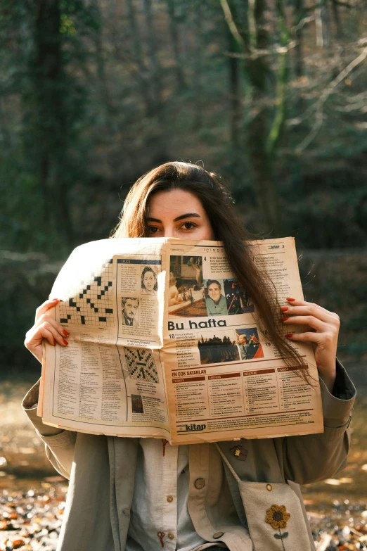 a woman holds up the pages of the newspaper