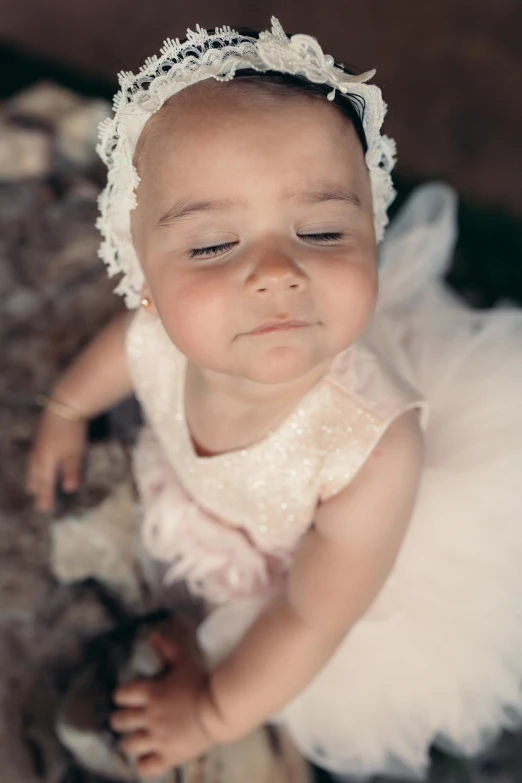 a little baby in white dress with her face up