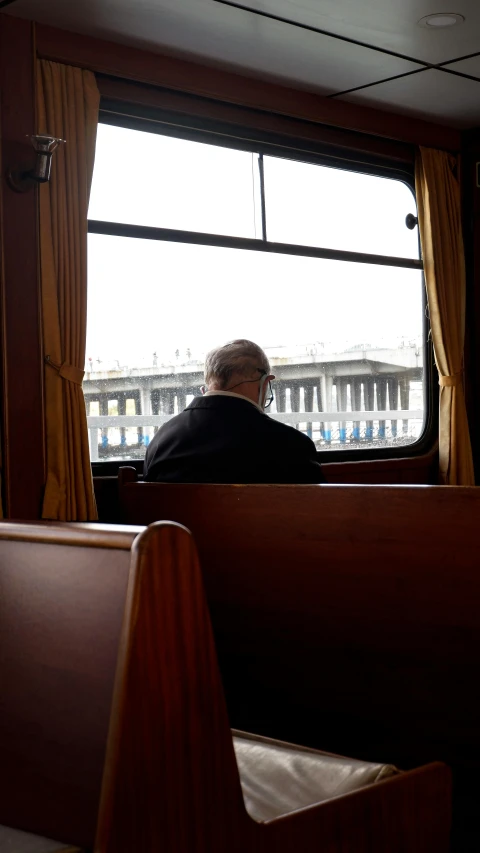 the man is sitting in a booth looking outside