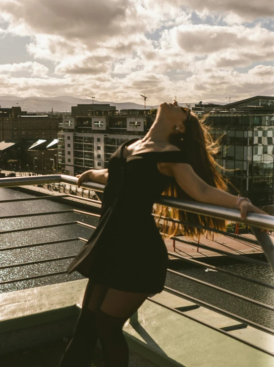 a young lady standing next to railing looking at the sky