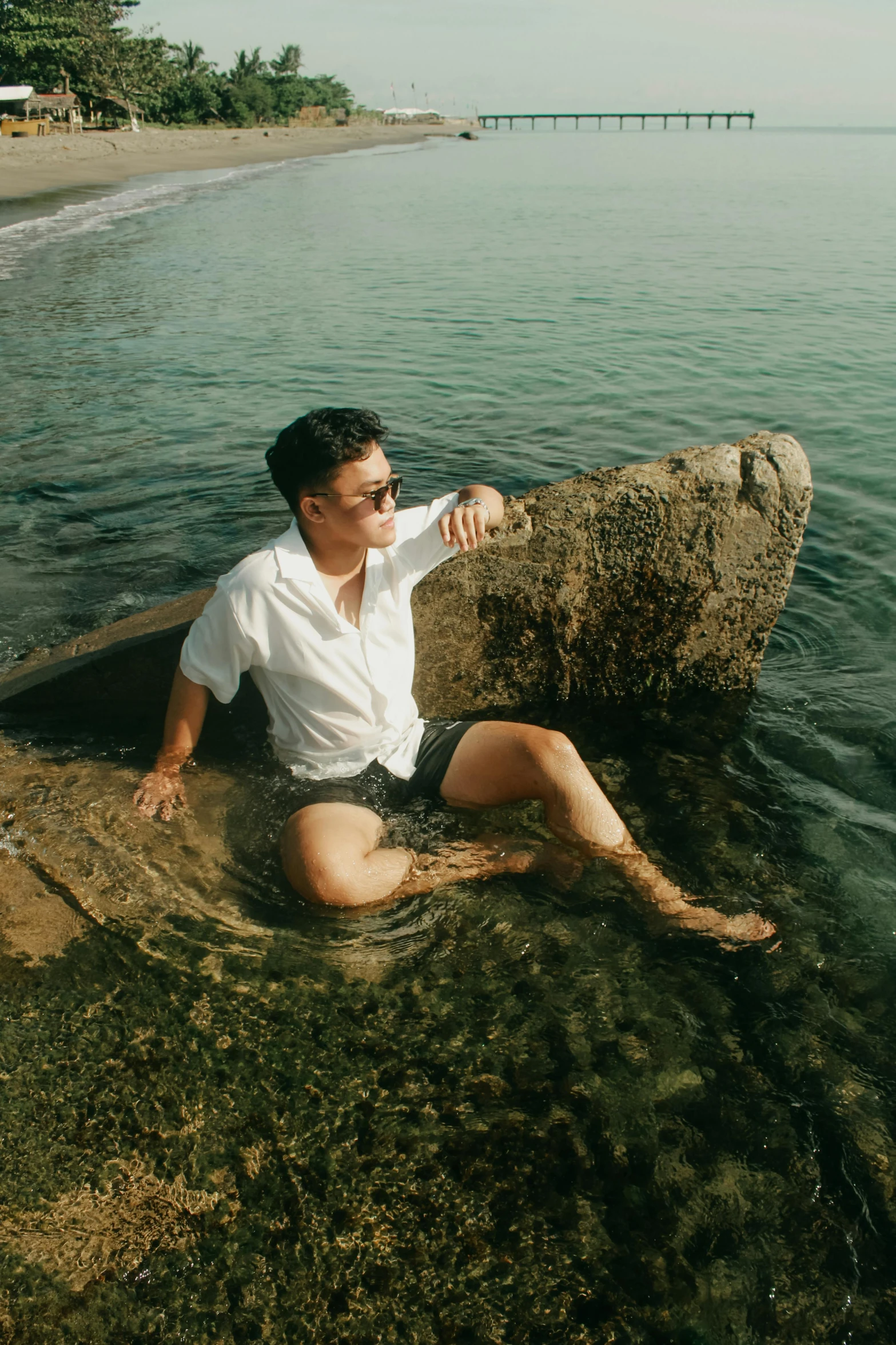 a man sitting in the water on a rock