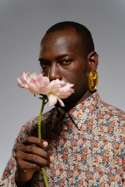 a man holding a flower next to his face