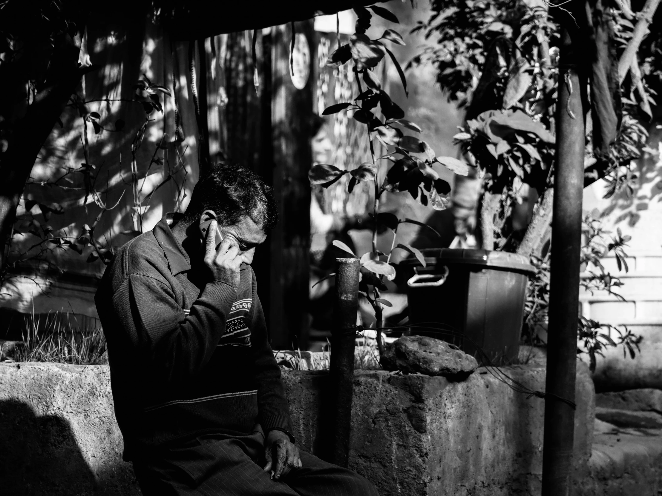 a black and white po of a man sitting and using his phone