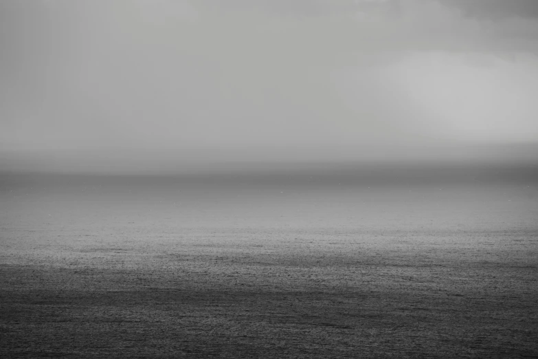 a black and white po of an ocean and cloudy sky