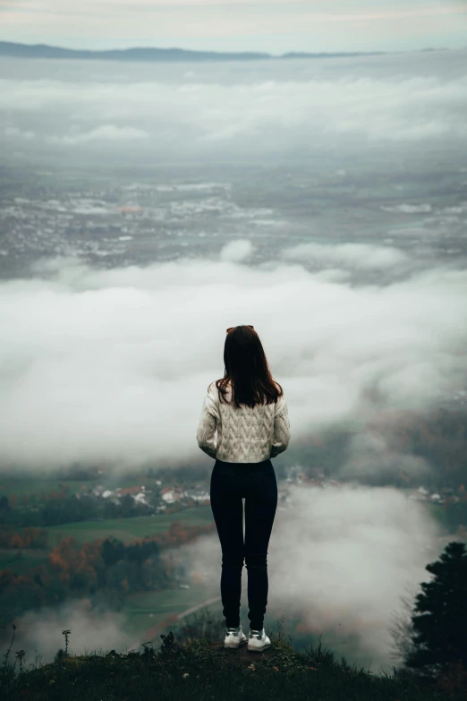 girl in white sweater looking out over the clouds